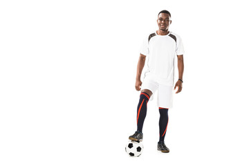 handsome young african american sportsman standing with soccer ball and smiling at camera isolated on white