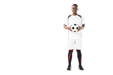 full length view of happy young african american soccer player holding ball and smiling at camera isolated on white