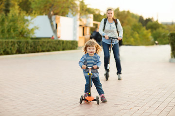 the mother walks with the child, ride scooters and Having Fun outdoors