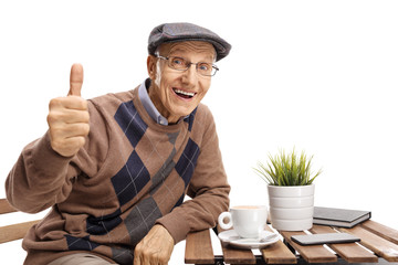 Senior sitting at a coffee table making a thumb up gesture