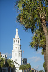 Fototapeta na wymiar St Michael's church spire with focus on palmetto palms in the foreground in Charleston, South Carolina.