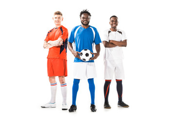 Fototapeta na wymiar full length view of multiethnic young soccer players standing together and smiling at camera isolated on white