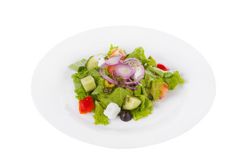 Greek salad with feta, olives, lettuce, red onion, cucumber, tomato, bell pepper, pesto on plate, white isolated background Side view. For the menu, restaurant bar cafe