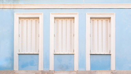 Wooden white retro style windows with shutters, on blue painted wall.