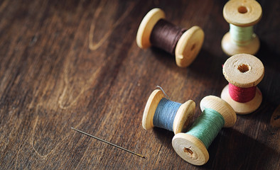 Fototapeta na wymiar Sewing thread on a wooden background. Set of threads on bobbins 