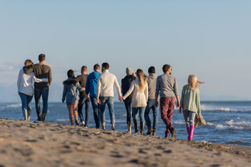 Group of friends running on beach during autumn day