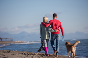 couple with dog having fun on beach on autmun day