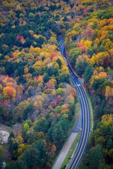 A car driving on a road surrounded by fall color in New England - aerial - 223367790