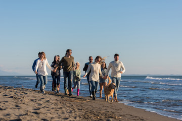 Group of friends running on beach during autumn day