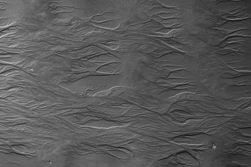 Sand surface with unusual patterns. Water made pictures on a sand while low tide. Black and white.