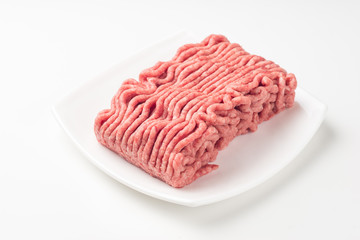 Plate with fresh raw ground beef isolated on white