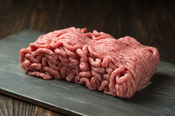 Raw minced meat in a plate on wooden background