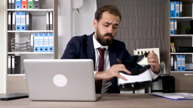 Businessman works on the computer than picks up a VR headset and start creating in virtual reality. Augmented reality searching field in start up company office