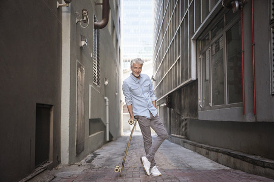 Mature man with longboard in an alley