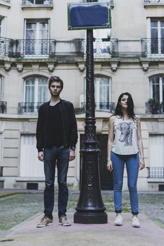 France, Paris, young couple standing at lamp post in front of urban building