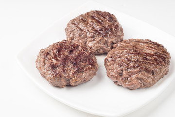 Homemade cutlets on a white plate and white background.