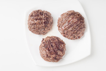 Homemade cutlets on a white plate and white background.