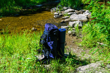 Touristic backpack on a bank of river in forest