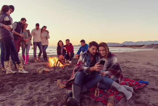 Couple enjoying bonfire with friends on beach