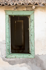 Broken old wooden window on weathered wall.