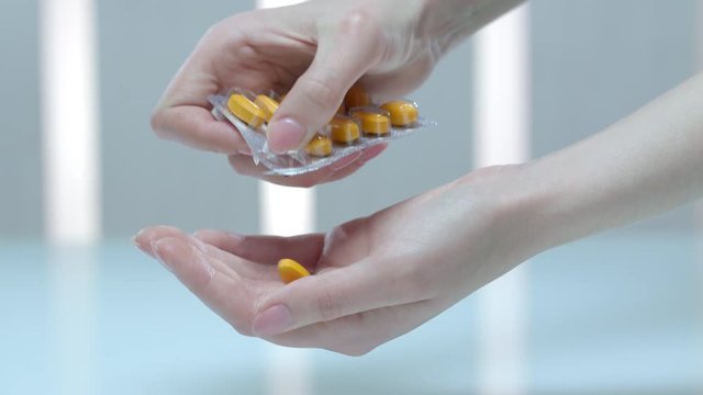 Female hand take medicaments dose. Close up of woman pour tablet from blister. Prescription drugs in woman hand