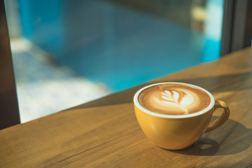 Hot art Latte Coffee in a cup on wooden table and morning light