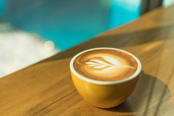 Hot art Latte Coffee in a cup on wooden table and morning light