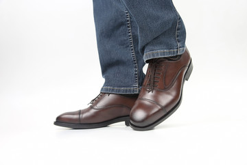 Men's legs in jeans shod in classic brown Oxford shoes