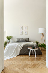 Eco style bedroom interior with a bed dressed in graphite linen and vanilla blanket. Herringbone...
