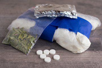 suspected drug trafficking, unknown pills, white powder in a transparent package and the foil and similar to the "spice" mixture, lay on a brown table