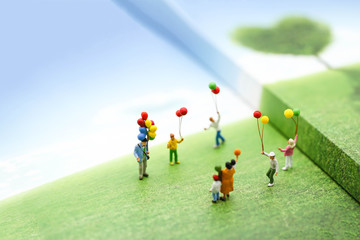 Fototapeta na wymiar Miniature people with family holding balloon on the map with sunlight, happy family day concept.