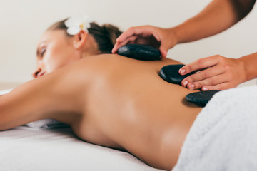 Obraz na płótnie Canvas relaxing woman having stone therapy at spa salon