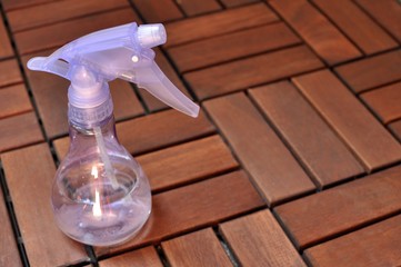 Sprinkler, violet watering can on brown natural wooden background with copy space