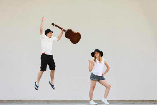 Man jumping with guitar, woman pointing at him