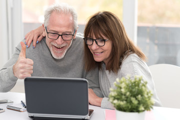 Happy mature couple having a good surprise on laptop