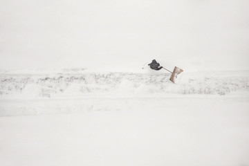janitor cleans the snow-covered parking space during the snow season. Winter time.
