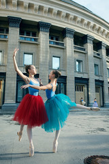 Obraz premium Ballet dancers dancing on street. Young ballerinas in color tutus. Ballet feet on the point