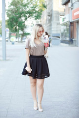 Outdoor fashion hipster style portrait of beautiful blonde woman drinking cocktail on the street