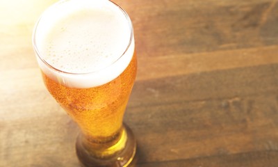 Glass of light beer on background