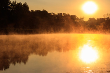 Fototapeta na wymiar View of river in the mist at sunrise. Fog over river at morning