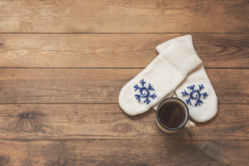 iron mug with coffee and knitted mittens on the wooden floor. Winter concept