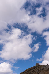 Fototapeta na wymiar Rifugio sulla cima della montagna con cielo azzurro con nuvole bianche 