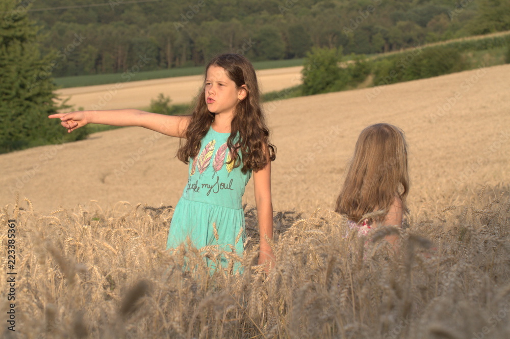 Wall mural two little girls sister walking on a wheat field