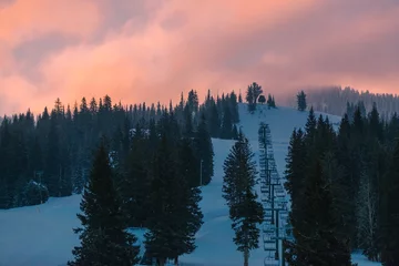 Fototapete Wald im Nebel Sonnenaufgang über einem Skigebiet in den verschneiten Bergen