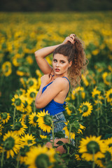 Young beautiful woman in a dress among blooming sunflowers. Agro-culture.