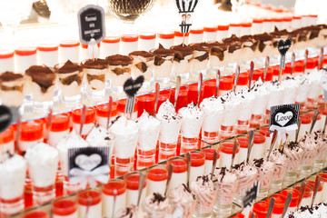 Fototapeta premium Delicious sweets on wedding candy buffet with desserts, cupcakes