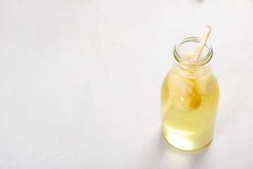 Bottle with tasty melon ball drink on light table. Space for text