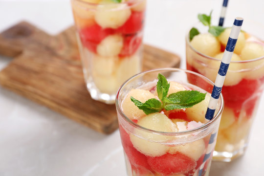 Glasses with tasty melon and watermelon ball drink on light table