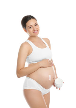 Pregnant woman applying body cream on belly against white background