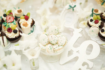 Delicious and tasty dessert table with cupcakes shots at reception closeup